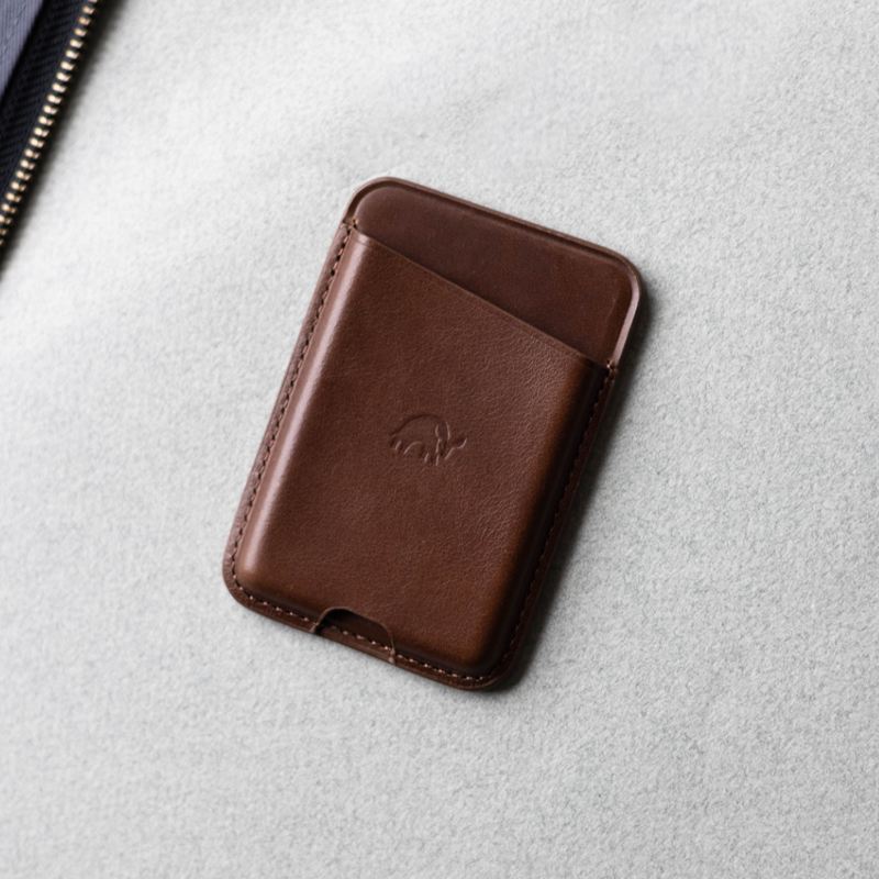Brown leather card wallet with embossed mammoth logo on light gray felt background