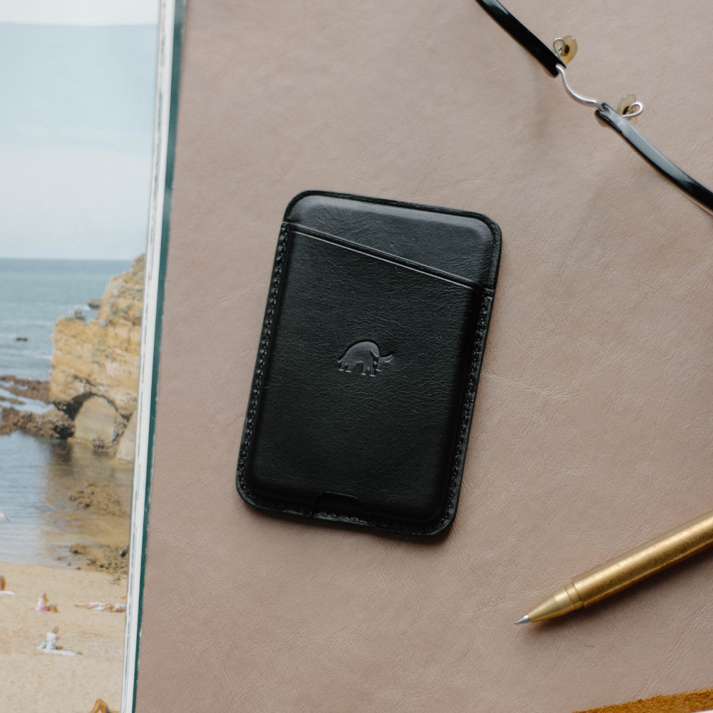 Black leather NavSafe wallet with embossed logo on a textured surface