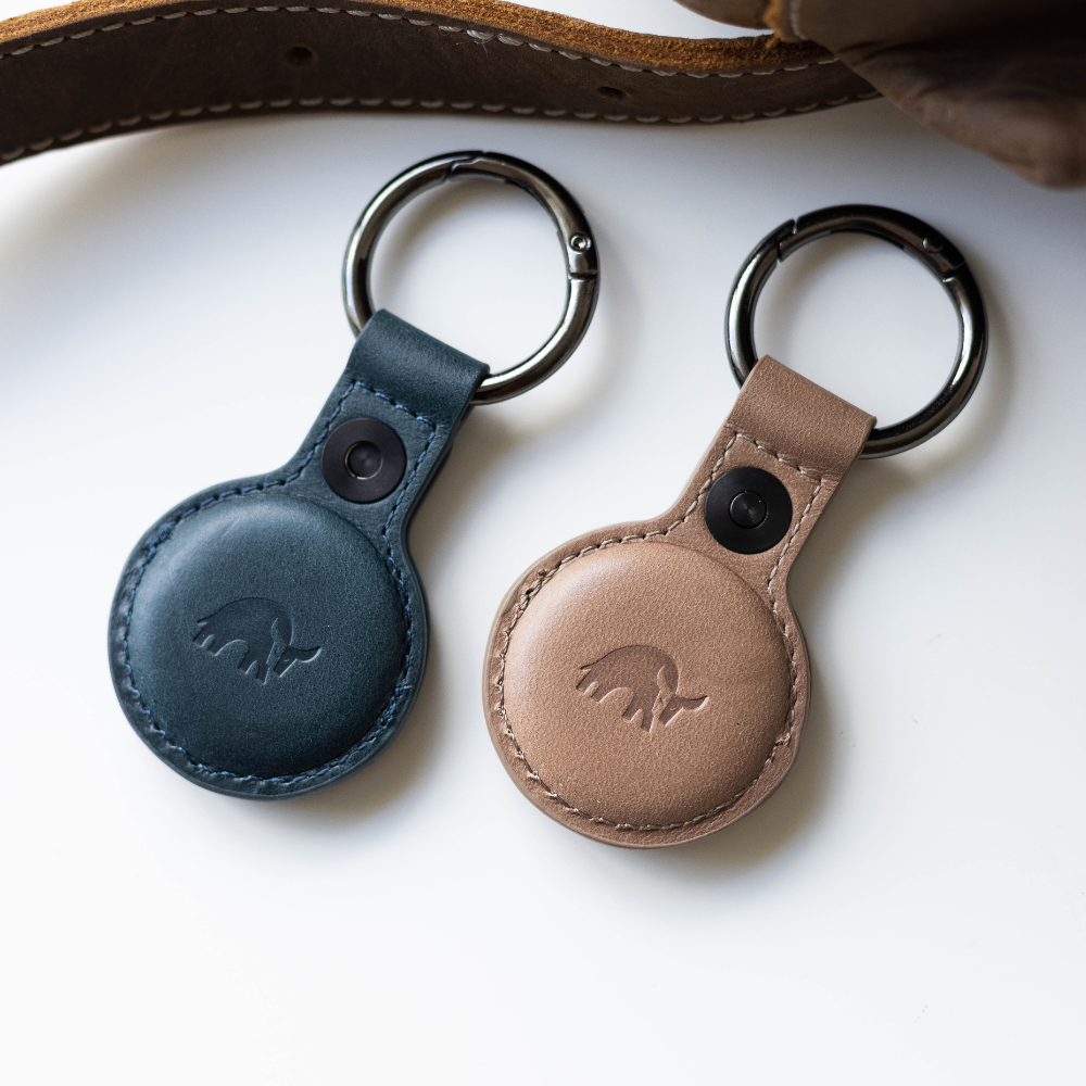 Two BullTags for AirTag in ocean blue and tan leather with a keyring attachment.