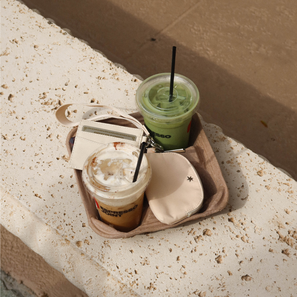 Buttercream Carrie wristlet with cardholder and coin pouch on a café tray with two iced drinks