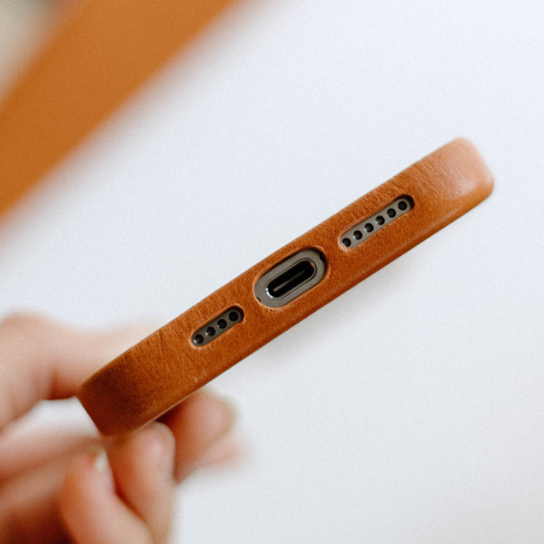 Bottom edge of Sienna Contemporary MagSafe leather phone case showing charging port and speaker cutouts and leather texture