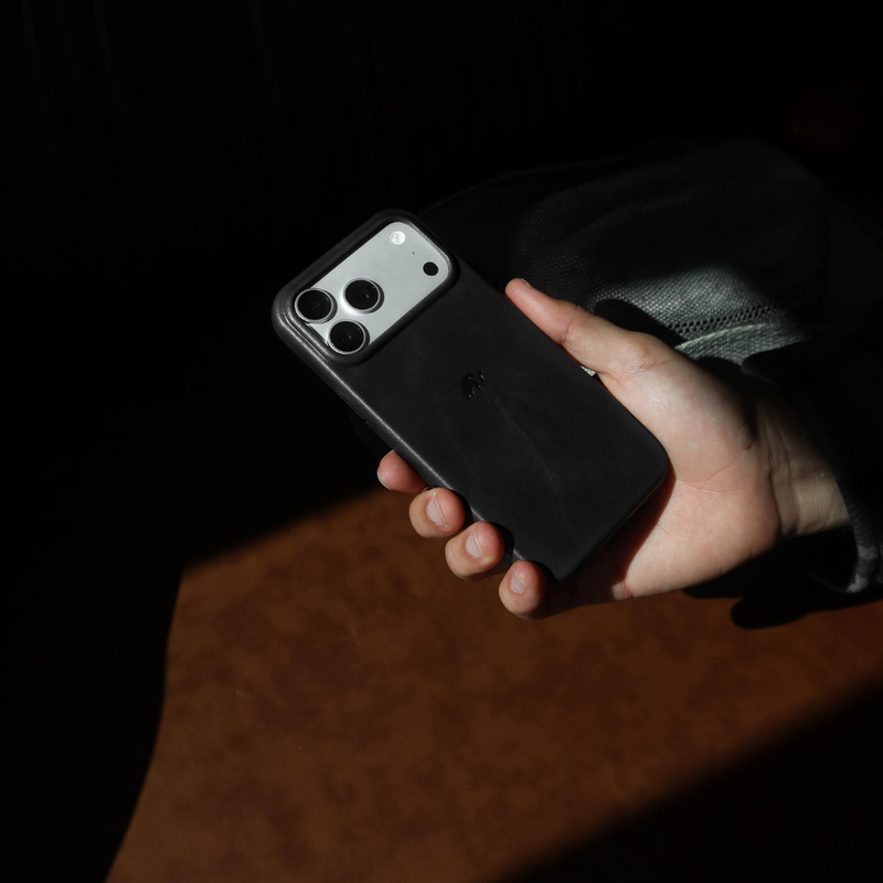Hand-held back view of Contemporary Plateau Case in black showcasing raised camera plateau and contoured finger grips on a dark, shadowed background
