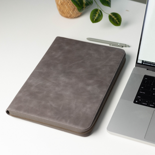 Leather MacBook Sleeve in Slate color, placed next to a laptop and pen on a desk.