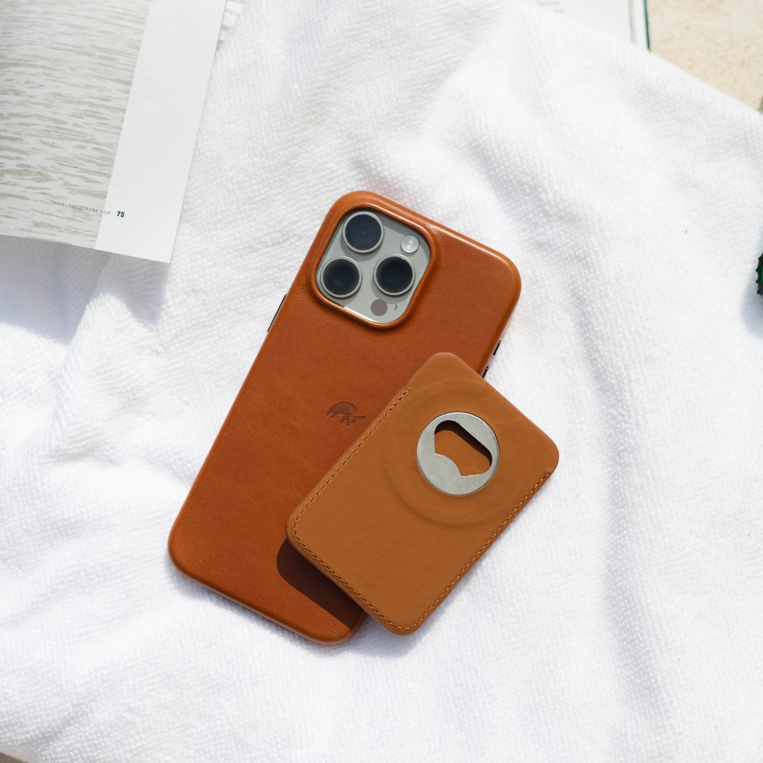 Top-down view of Sienna MagSafe Popper wallet and matching leather iPhone case showcasing stainless steel bottle opener on a white towel