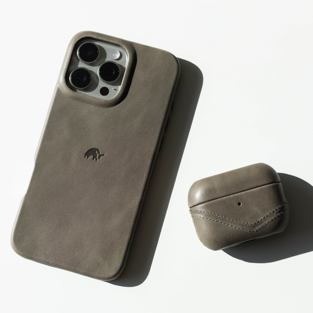 Gray-brown leather iPhone case with embossed elephant logo and matching AirPods case on white background, soft shadow.
