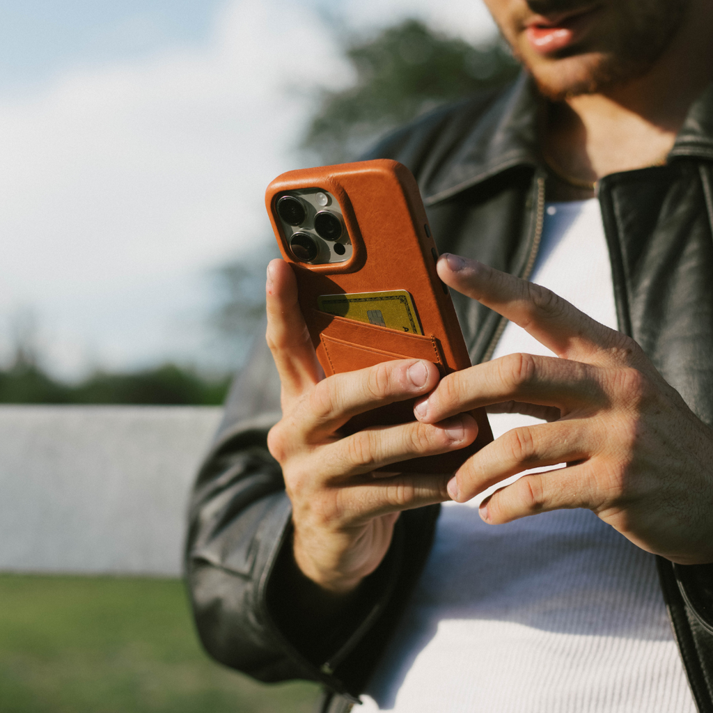 Man holding phone in sienna leather portfolio case with a card visible in the back pocket