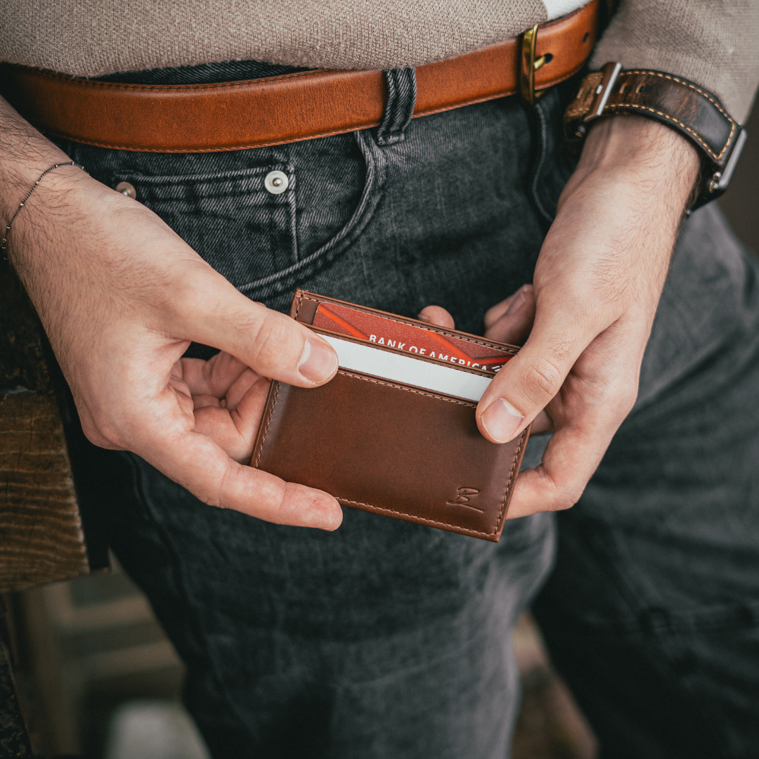 Hands holding a brown Bullstrap Reserve card wallet with a red BANK OF AMERICA card partially visible