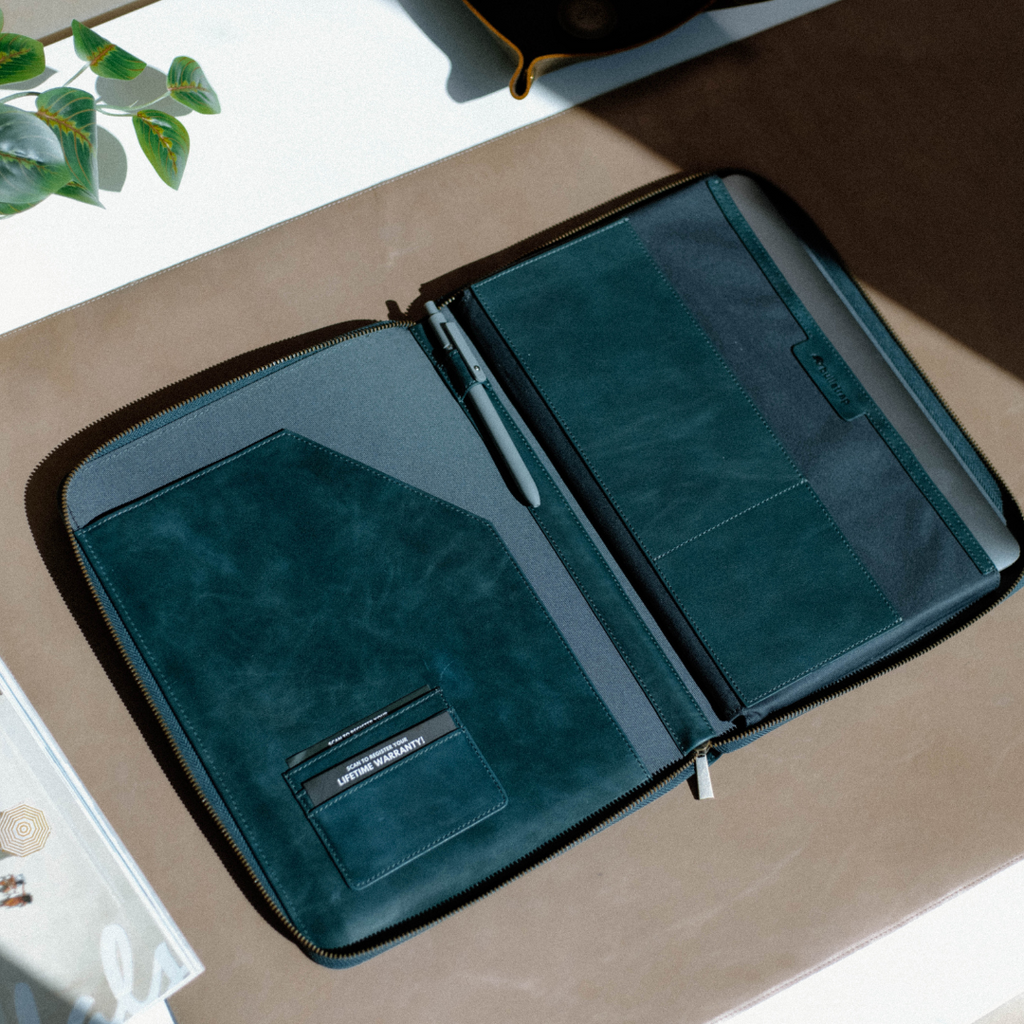 Teal zip folio organizer open showing a pen, card pocket labelled 'LIFETIME WARRANTY'.