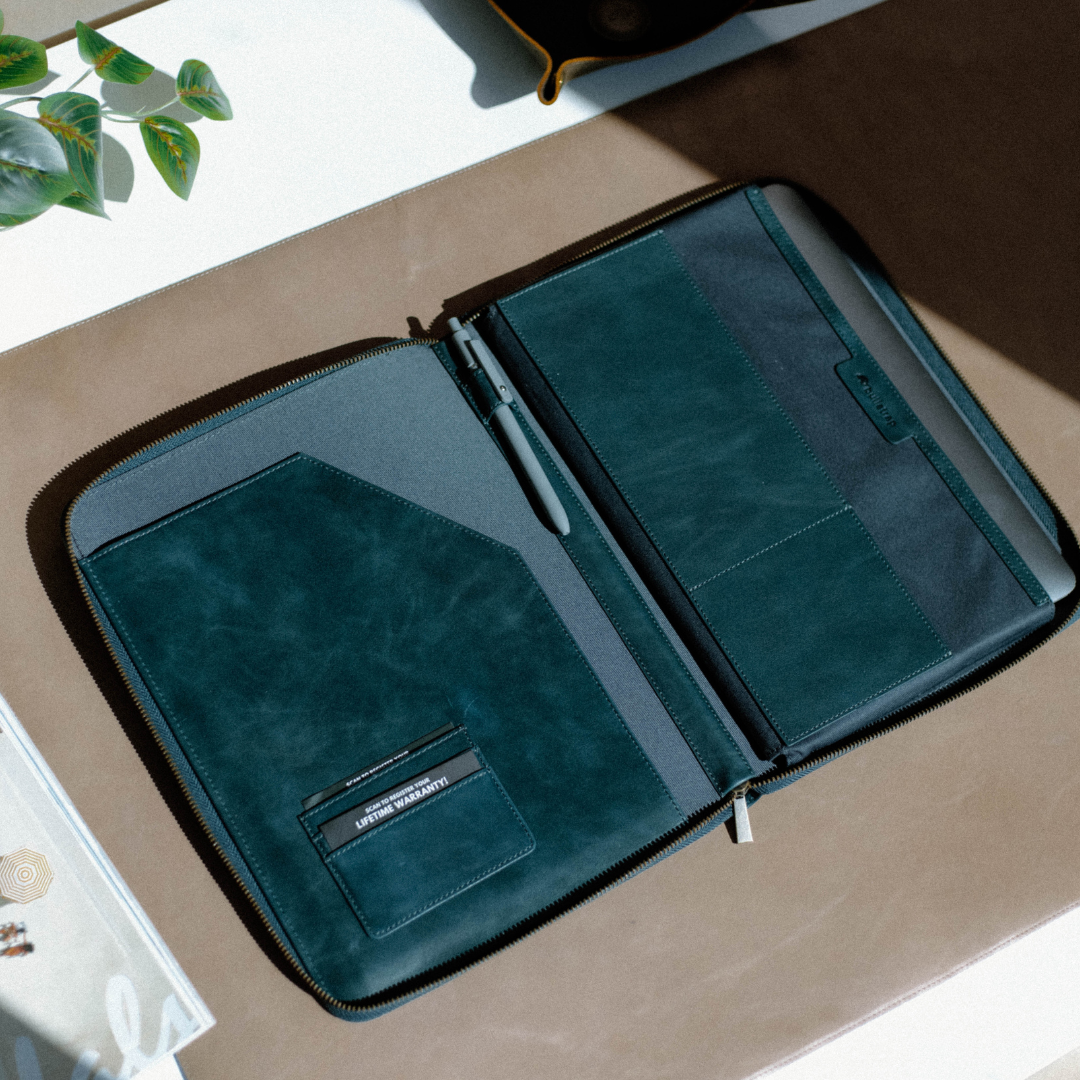 Teal zip folio organizer open showing a pen, card pocket labelled 'LIFETIME WARRANTY'.