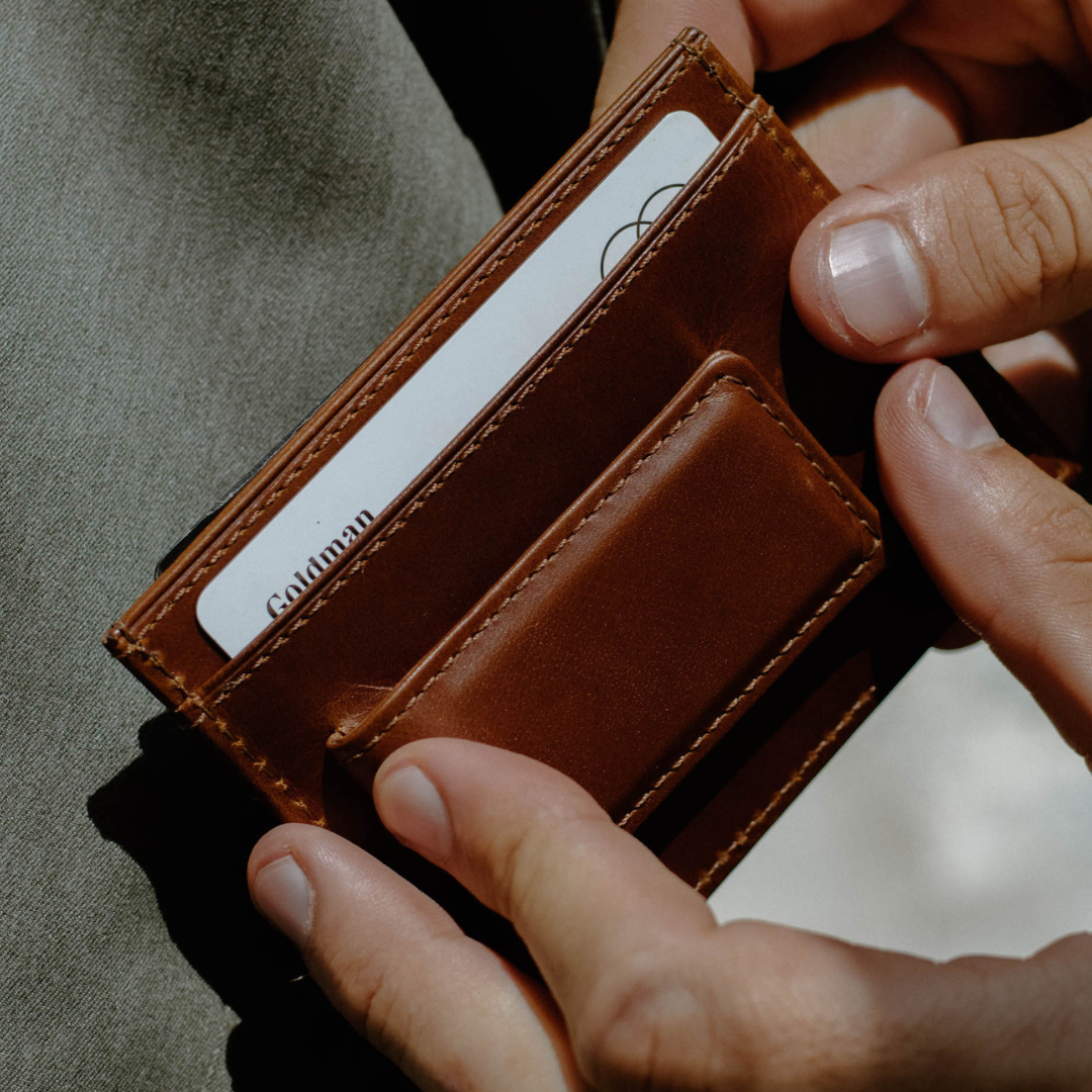 Brown leather Bullstrap Reserve "The Dealer" card wallet held in hands, card in slot showing text "Goldman".