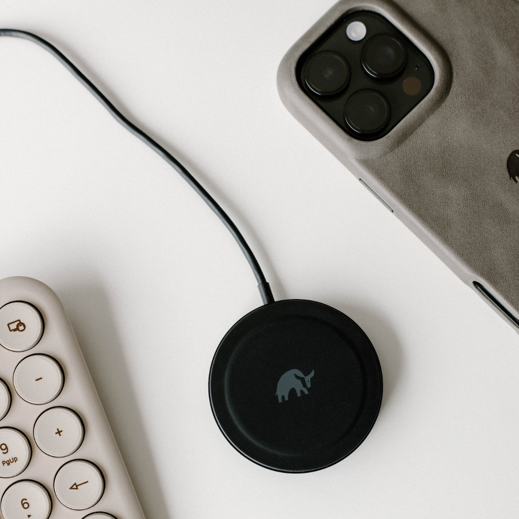 A black MagSafe charging cable next to a phone case and a keyboard