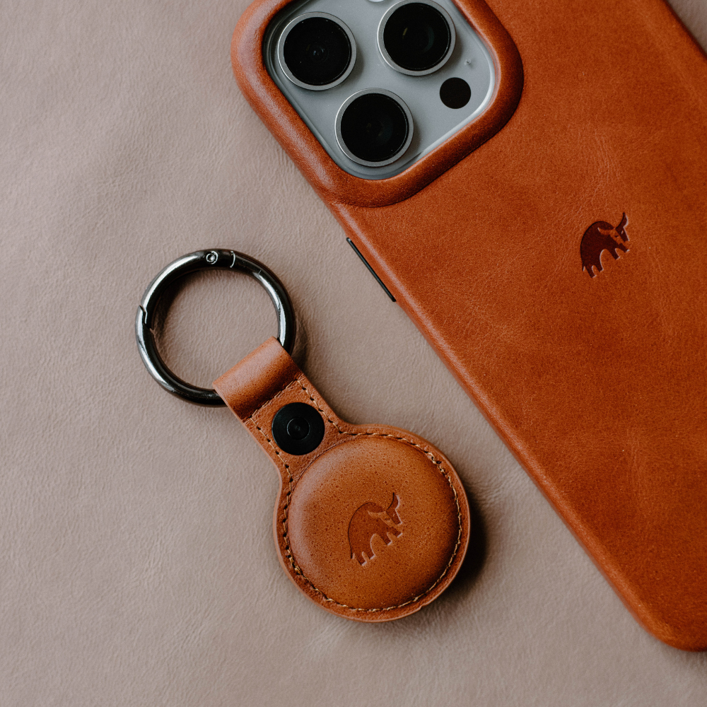 Brown leather BullTag for AirTag keychain next to a phone case with a similar design.