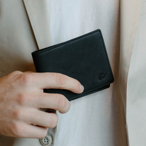 A person holding a black bifold wallet made of leather, featuring the Bullstrap logo.