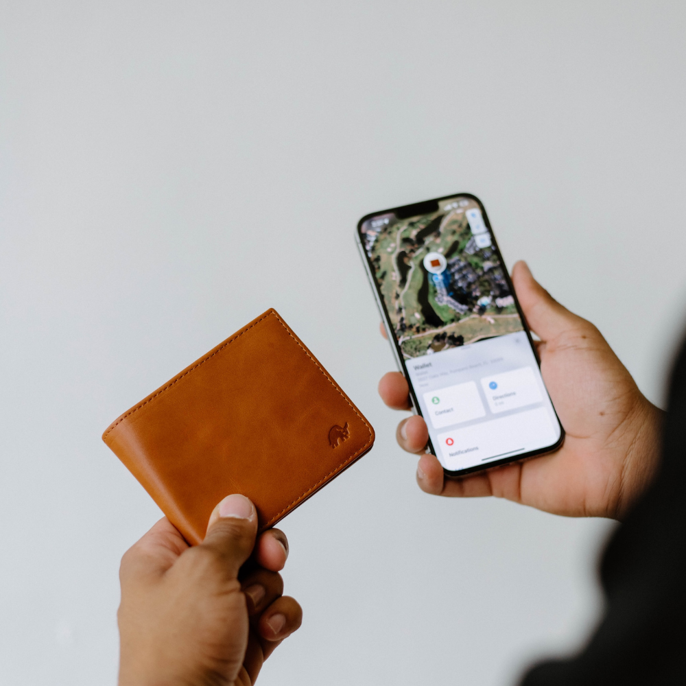 A person holding a leather bifold wallet and a smartphone showing a map.