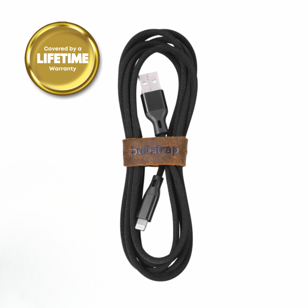 Black braided USB-A to Lightning cable with leather strap 'bullstrap'; gold seal says 'Covered by a LIFETIME Warranty'.