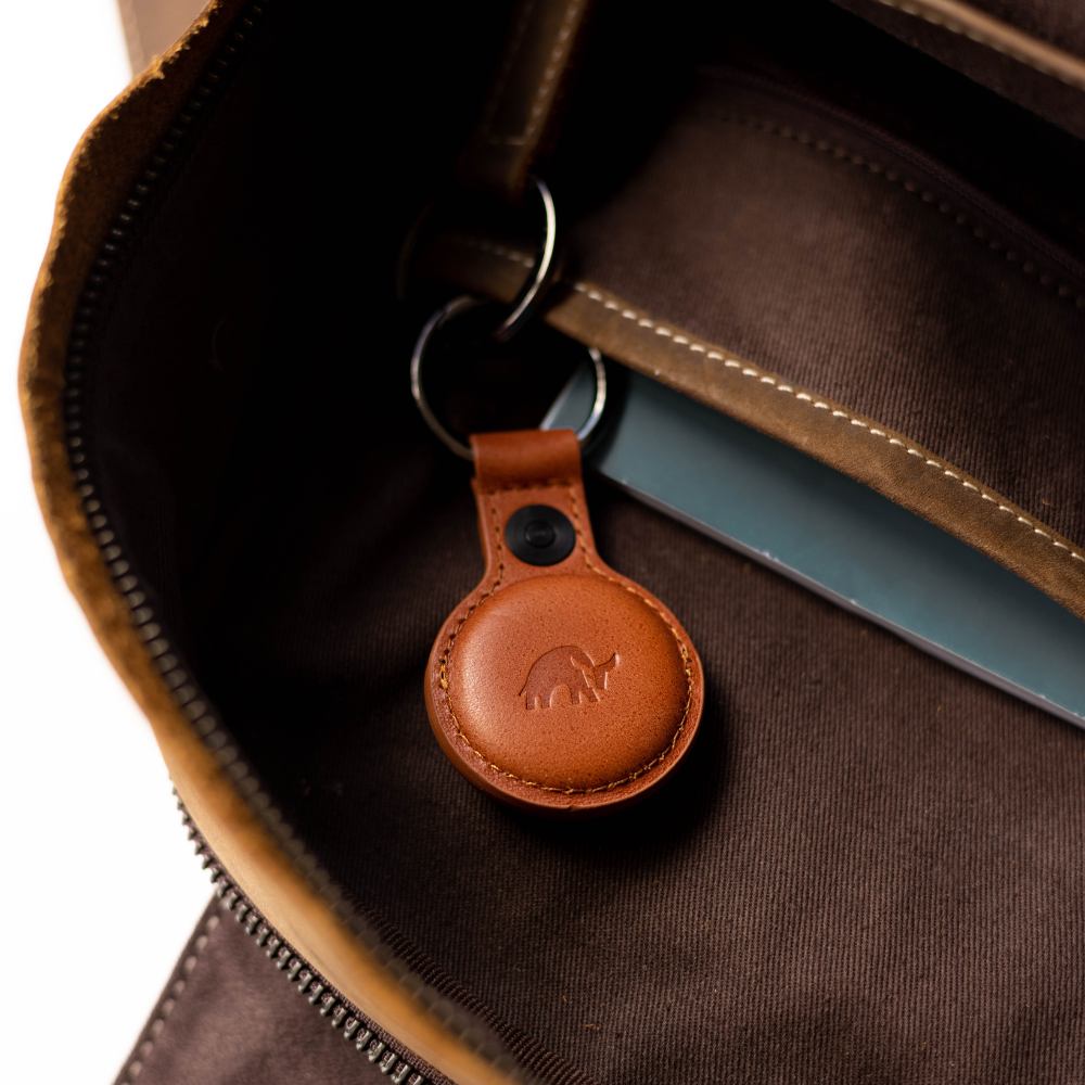A BullTag for AirTag in brown leather, attached to a keyring inside a brown bag.