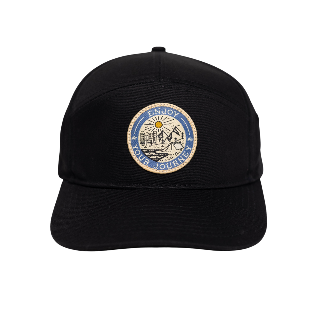 Black cap featuring a badge with 'ENJOY YOUR JOURNEY' and a mountain scene
