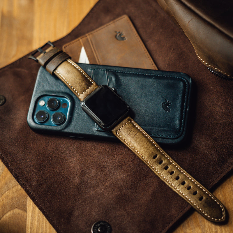 Leather Apple Watch strap on a phone and wallet, showcasing product use.