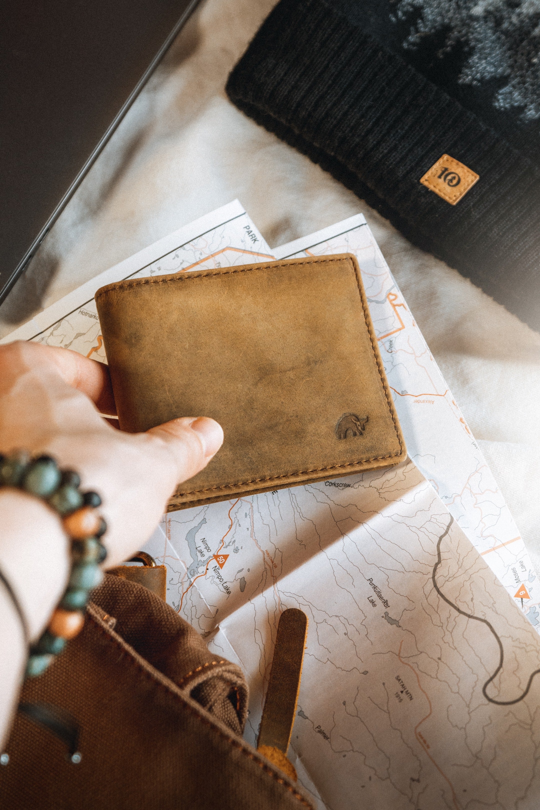 Hand holding brown leather wallet with embossed bull on folded map.