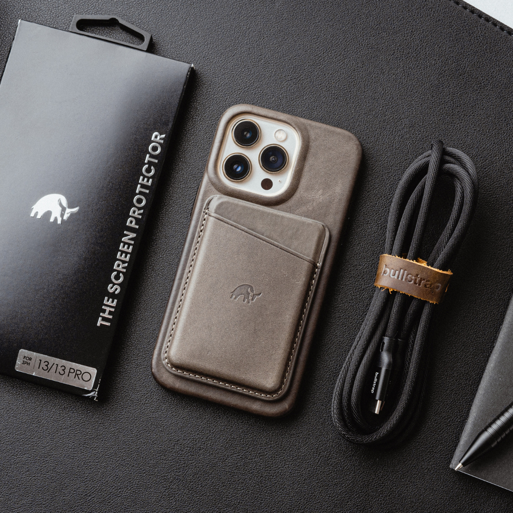 Brown leather iPhone case with card pocket, box labeled THE SCREEN PROTECTOR and FOR IPH 13/13 PRO; cable tag 'bullstrap'.