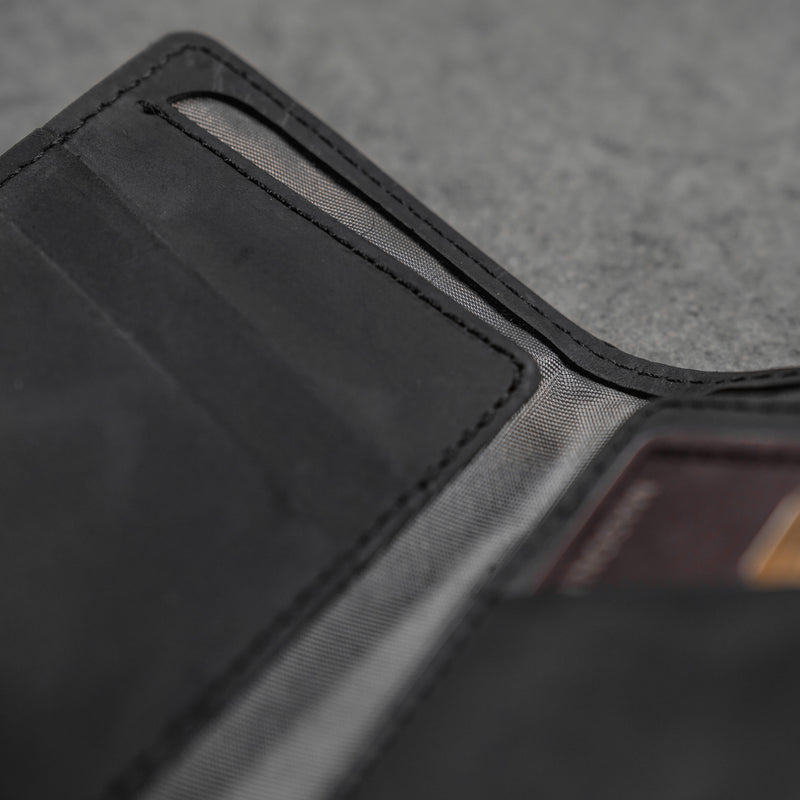 Close-up of a black leather bifold wallet interior showing card slots, mesh pocket and stitched seams.