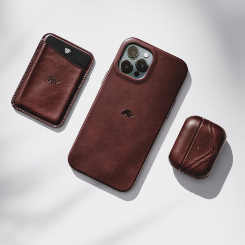 Leather phone case, wallet, and AirPods case in dark red color on a light background.