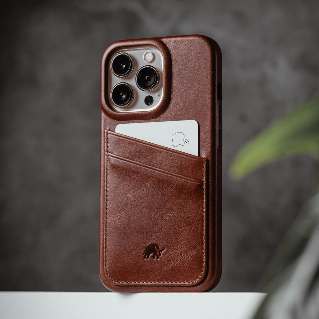Brown leather iPhone case with diagonal card pocket holding a white card showing an Apple logo