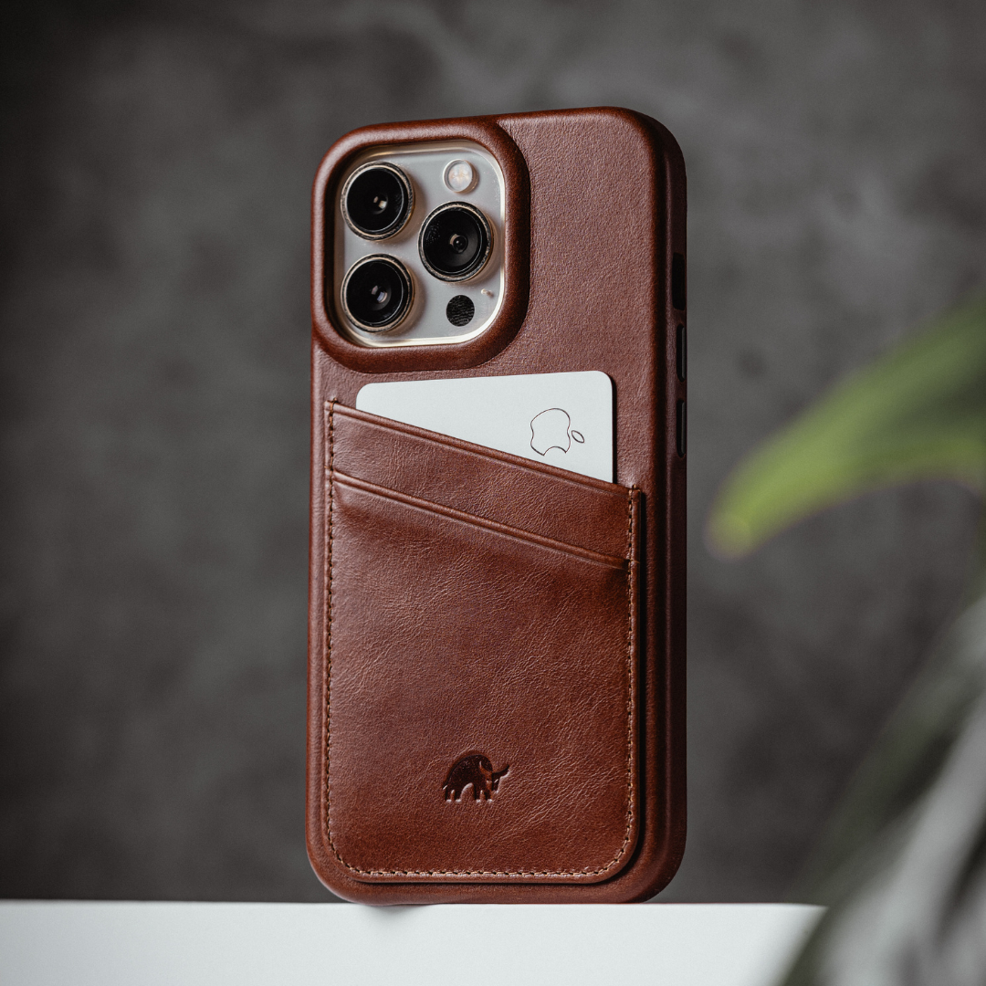 Brown leather iPhone case with diagonal card pocket holding a white card showing an Apple logo