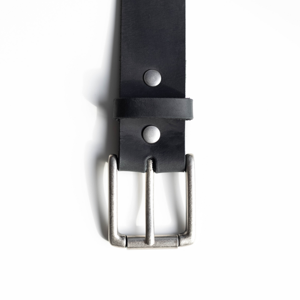 Close-up of a black leather belt with a silver buckle