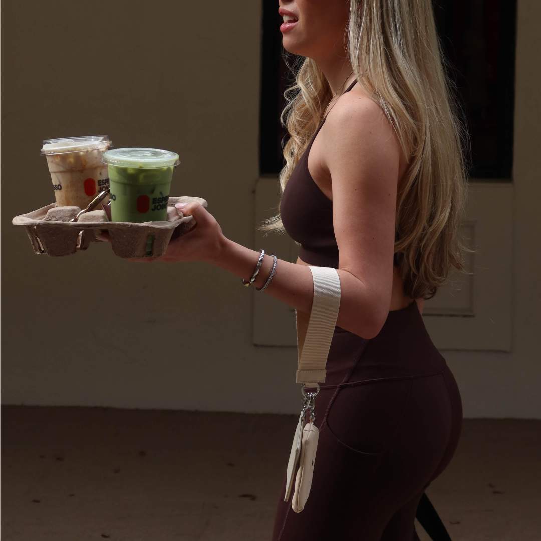 Woman in brown workout set holding a cardboard drink tray with two iced cups labeled ESPRESSO JONES.