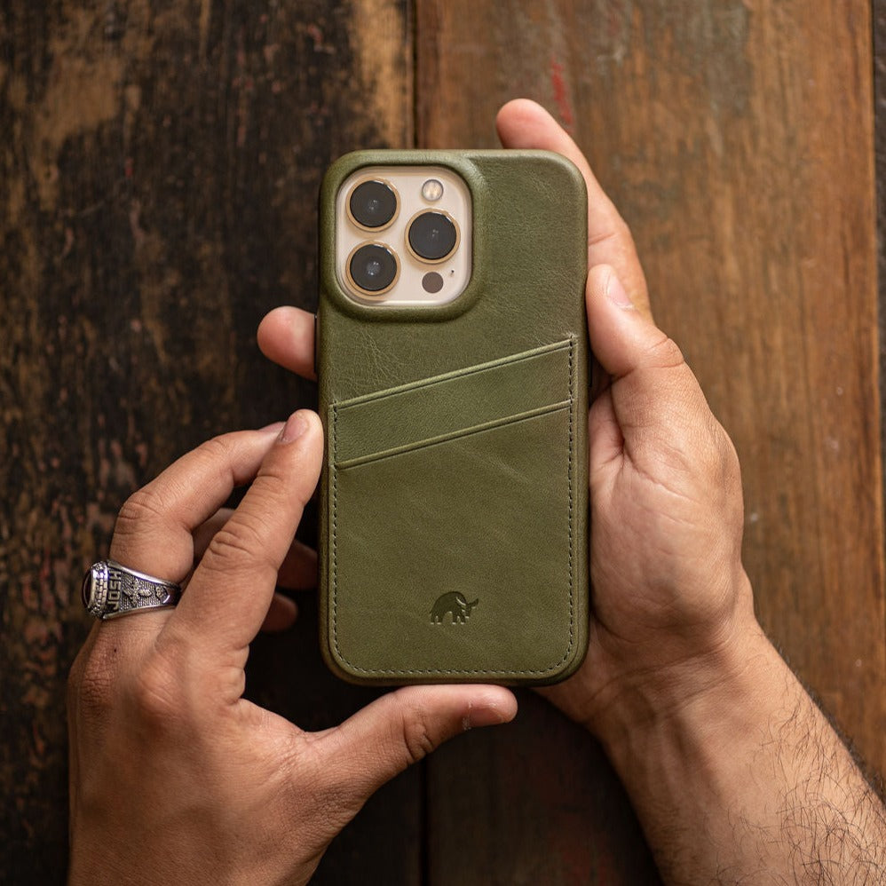 Green leather minimalist phone case with two diagonal card slots and small rhino logo, held in hands