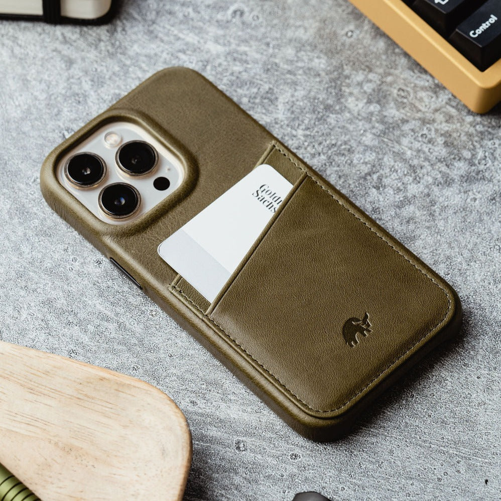 Olive leather iPhone case with rear card pocket holding white card; nearby keyboard key labeled Control.