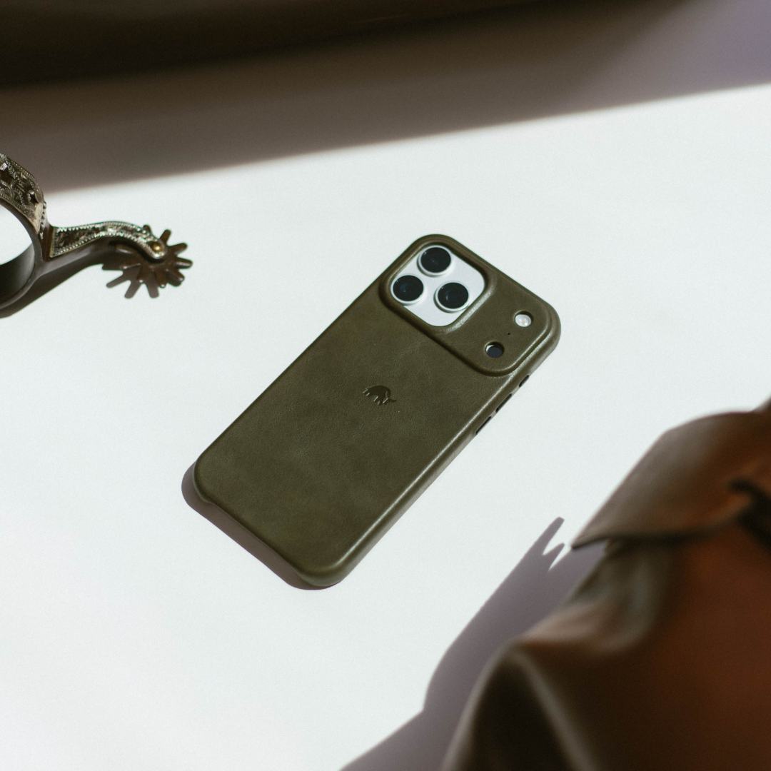 Olive-green leather phone case with raised camera lip and embossed elephant logo on white surface