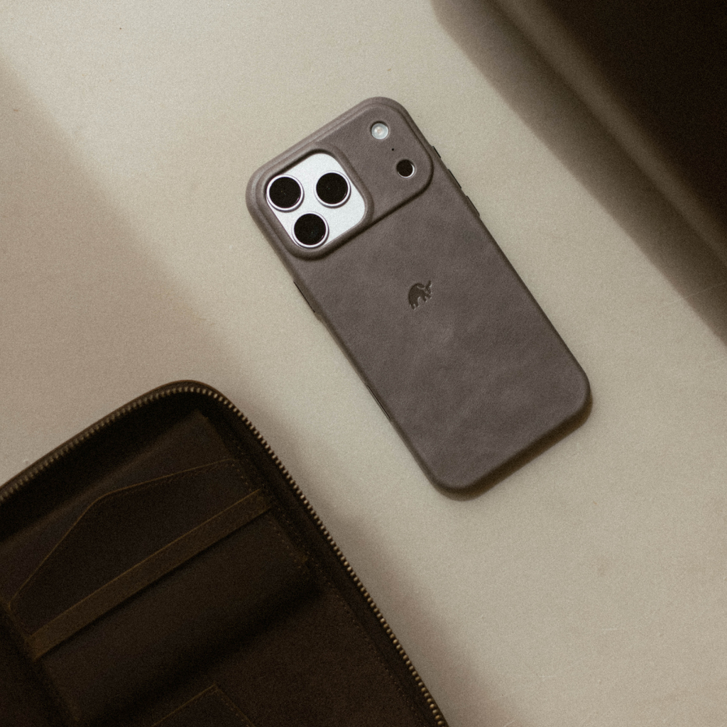 Slate leather smartphone case on a table next to a partially open zip wallet