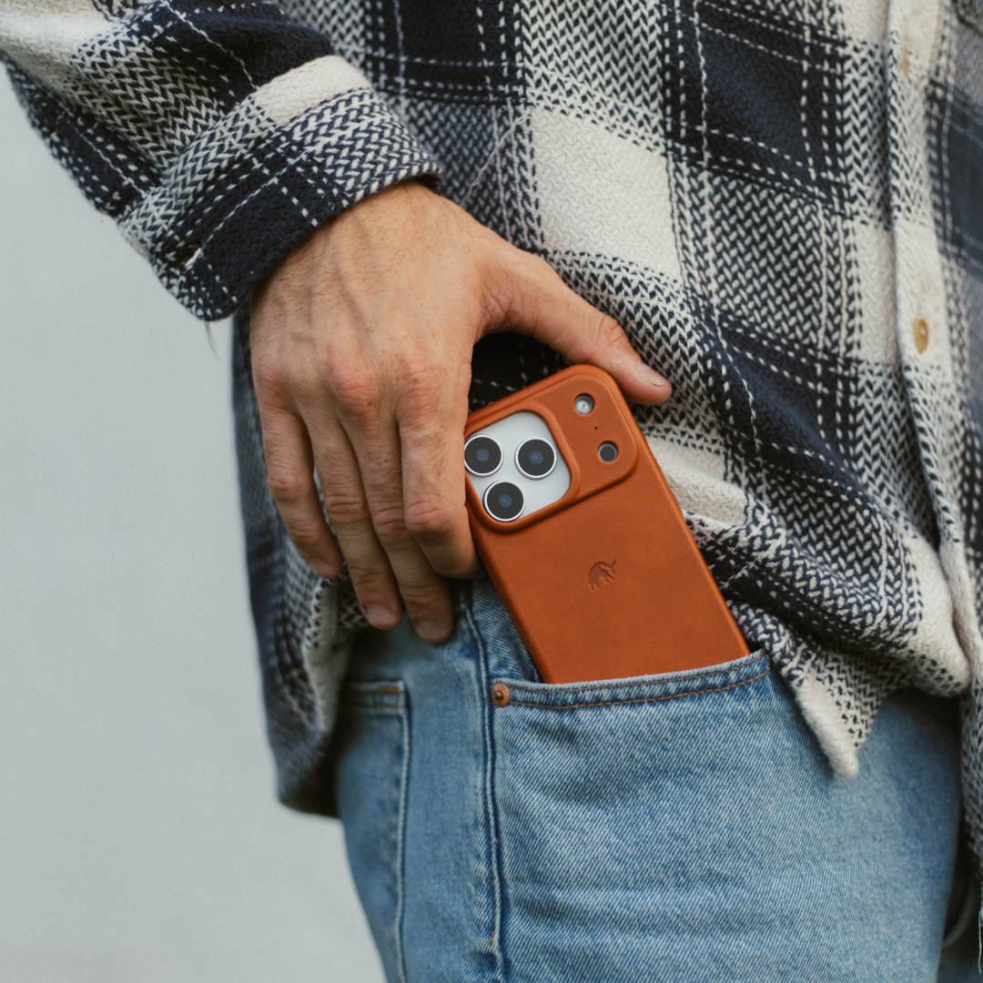 Hand sliding sienna leather phone case into back jean pocket