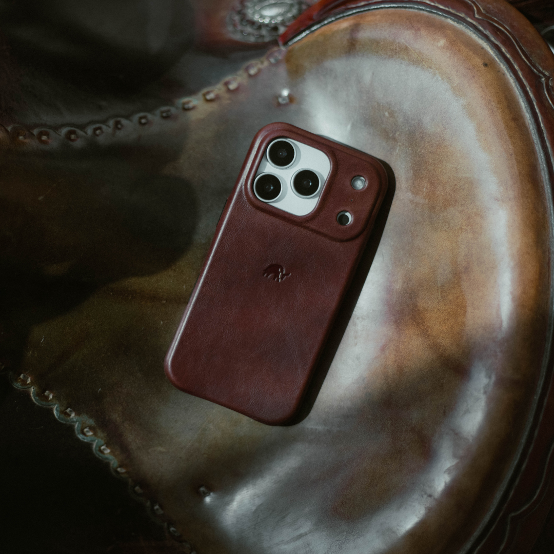 Bourbon leather minimalist phone case resting on stitched leather saddle
