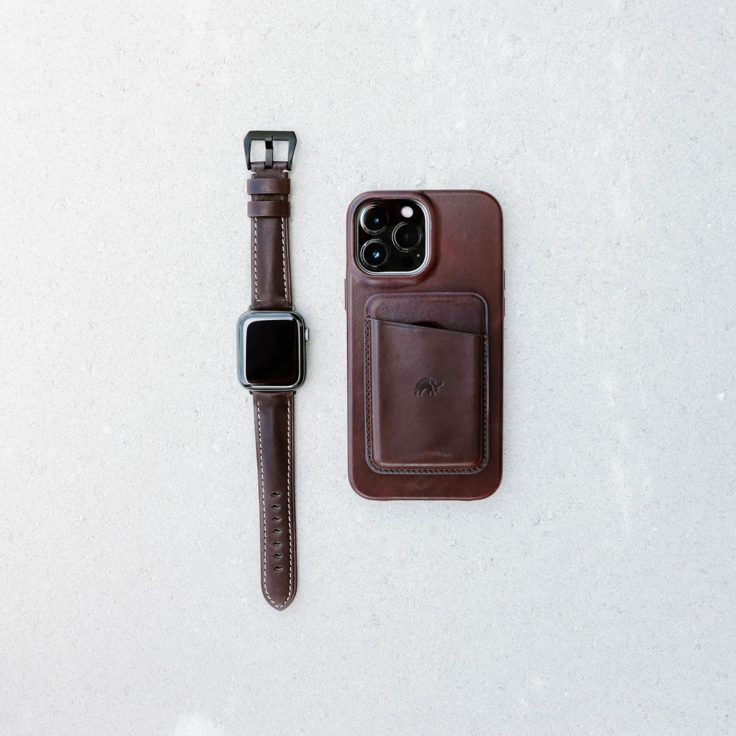 Leather Apple Watch Strap in Bourbon color next to a brown phone case on a light surface