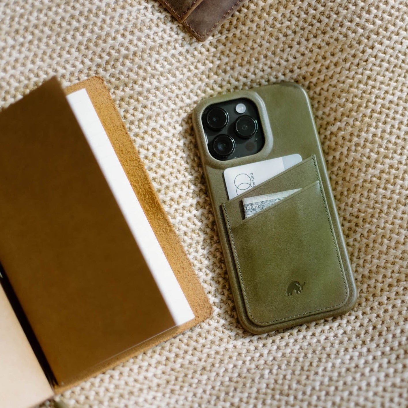 Olive green leather phone wallet case with two card slots holding a card and folded bill