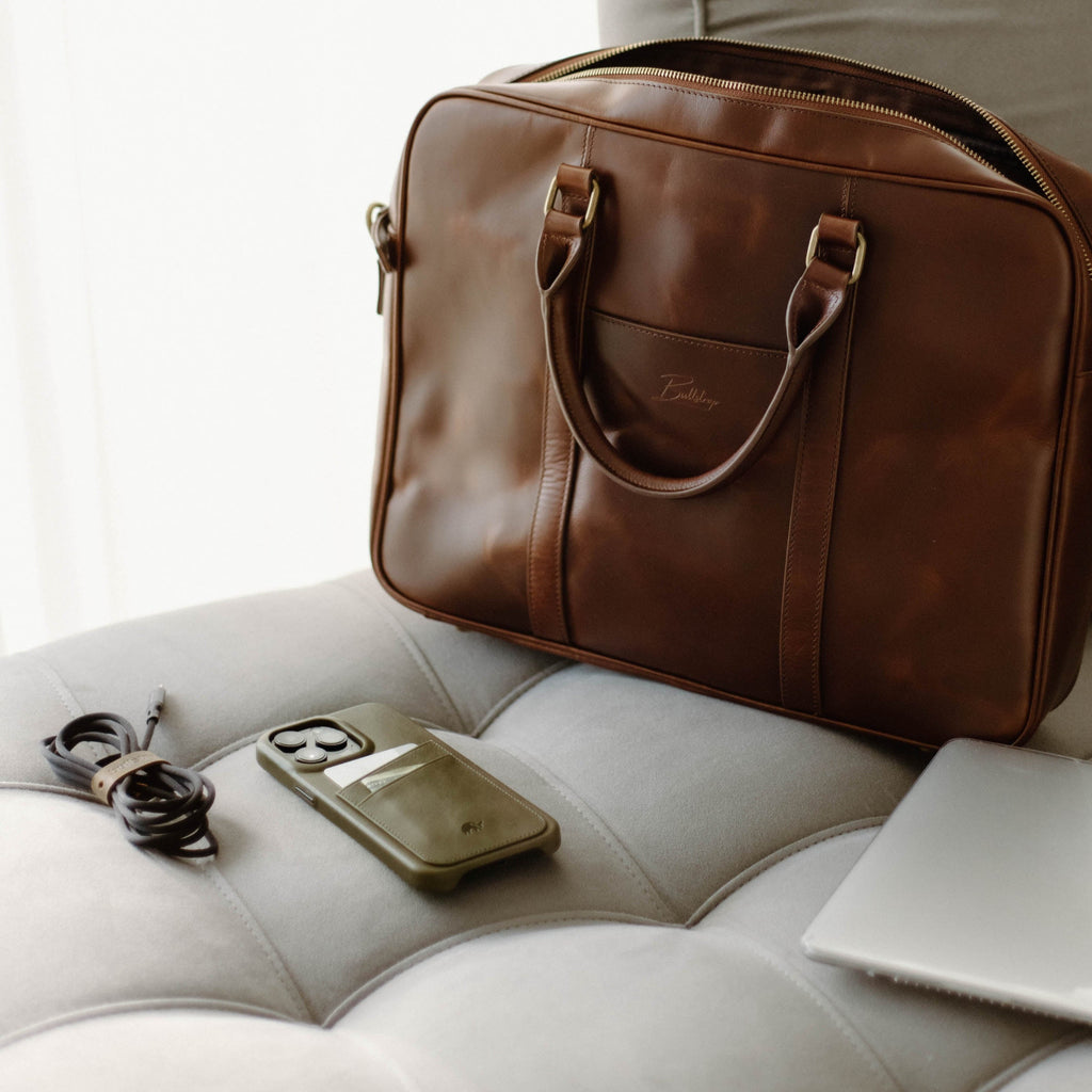 Brown leather minimalist portfolio case with handles; 'Bullstrap' logo on front