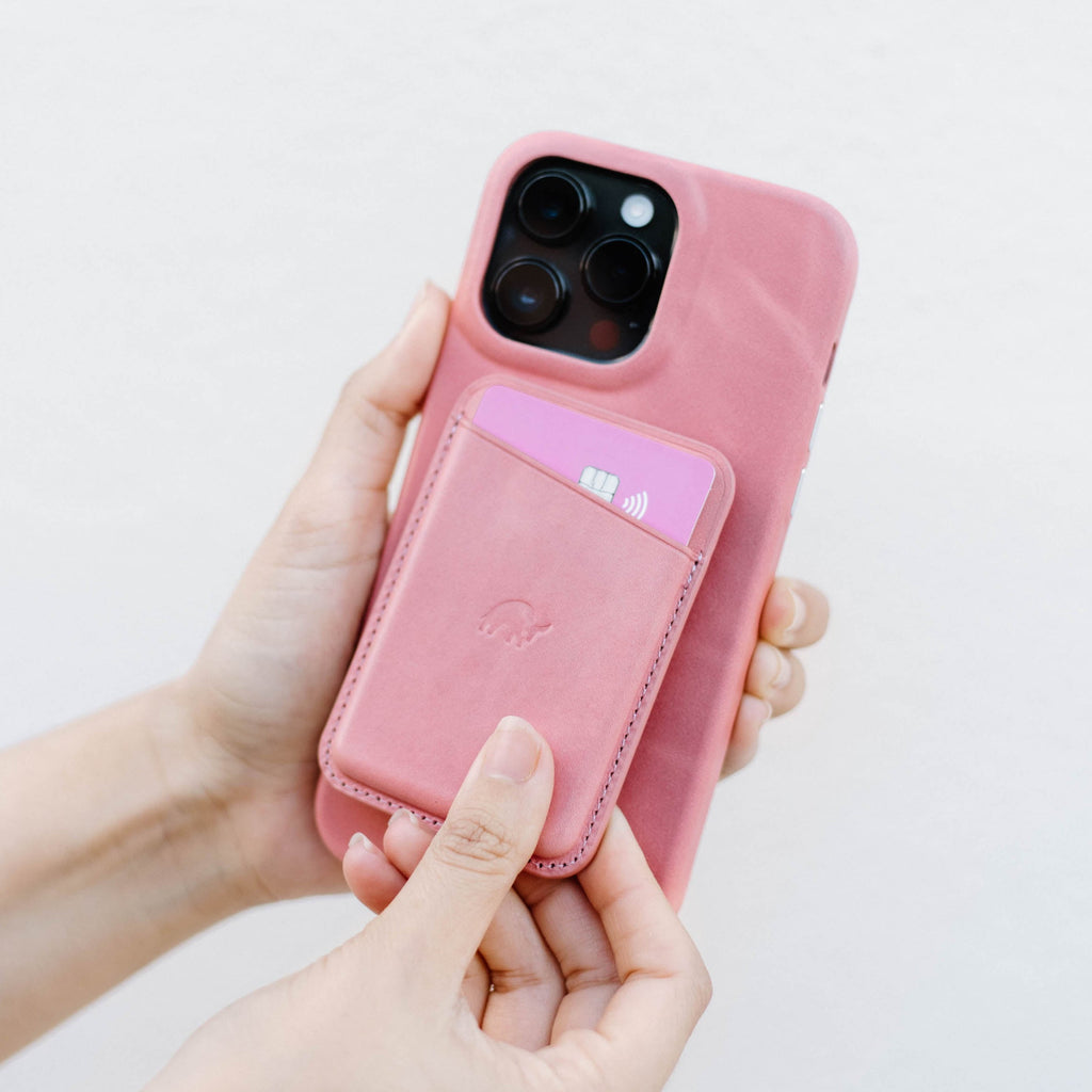 Person holding a pink phone case with a magnetic wallet and a card inside