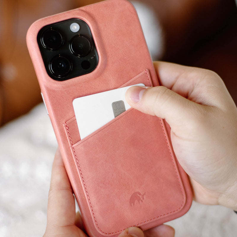 A person holding a pink leather iPhone case with a card in the slot.