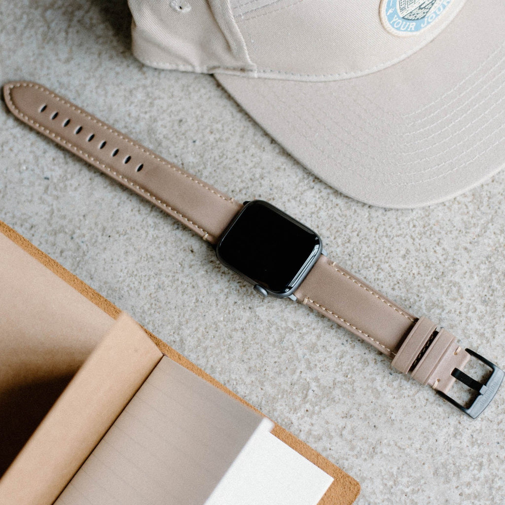 Leather Apple Watch Strap - Dune on a surface with a notebook and cap