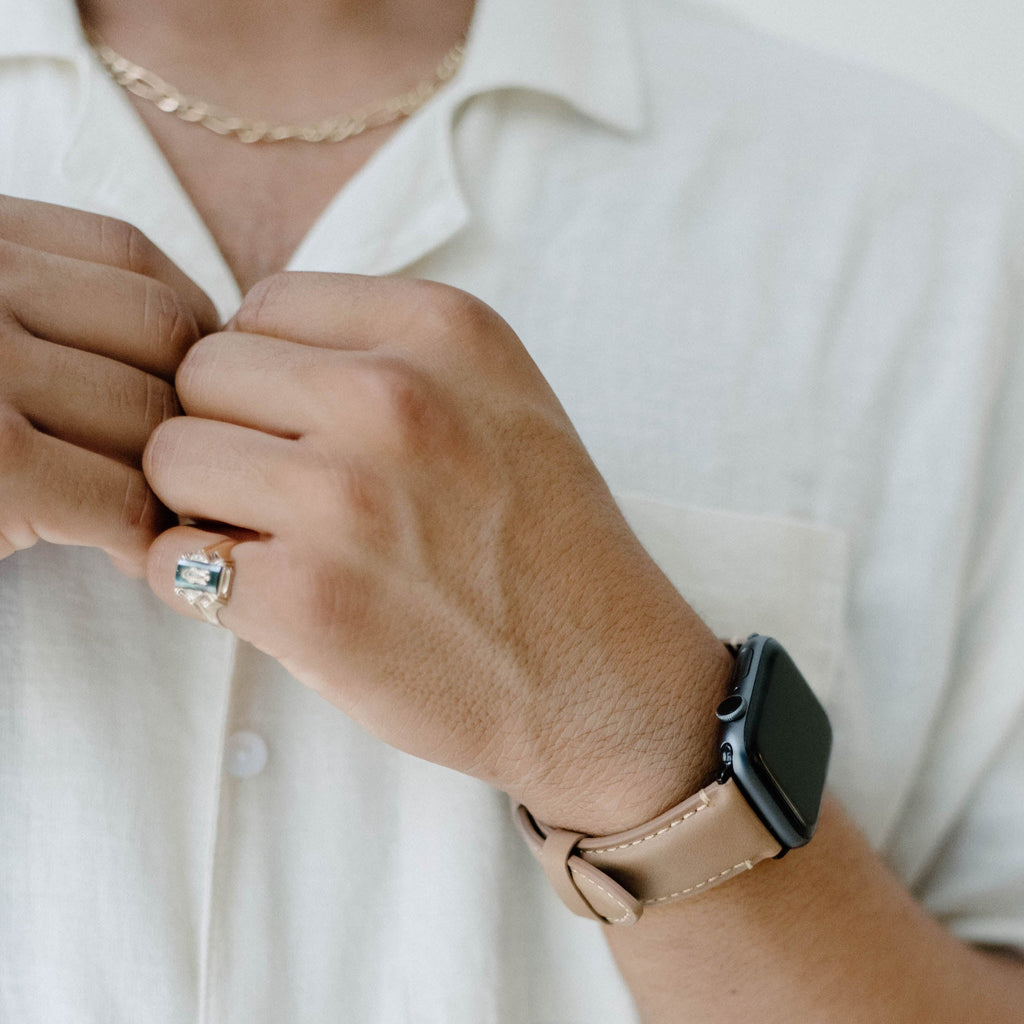 A person wearing a leather Apple Watch strap in Dune color, showcasing the strap's design and fit.
