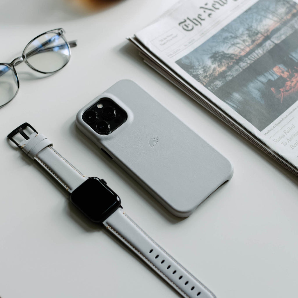 Minimalist iPhone Case in CLOUD color on a table with a watch and glasses