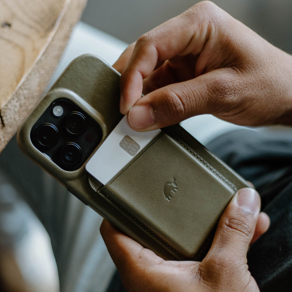 Olive-green leather phone case with stitched card pocket, card partially pulled out and embossed animal logo.