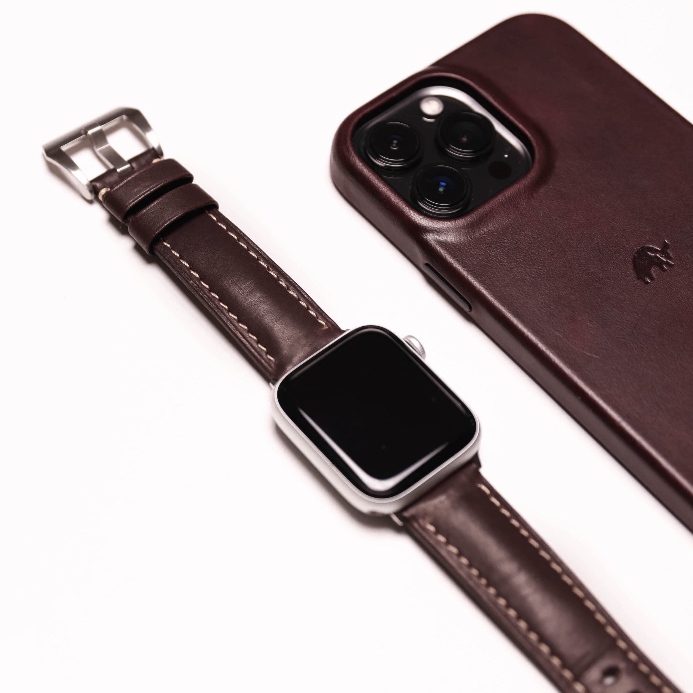 Brown leather Apple Watch strap next to a phone case
