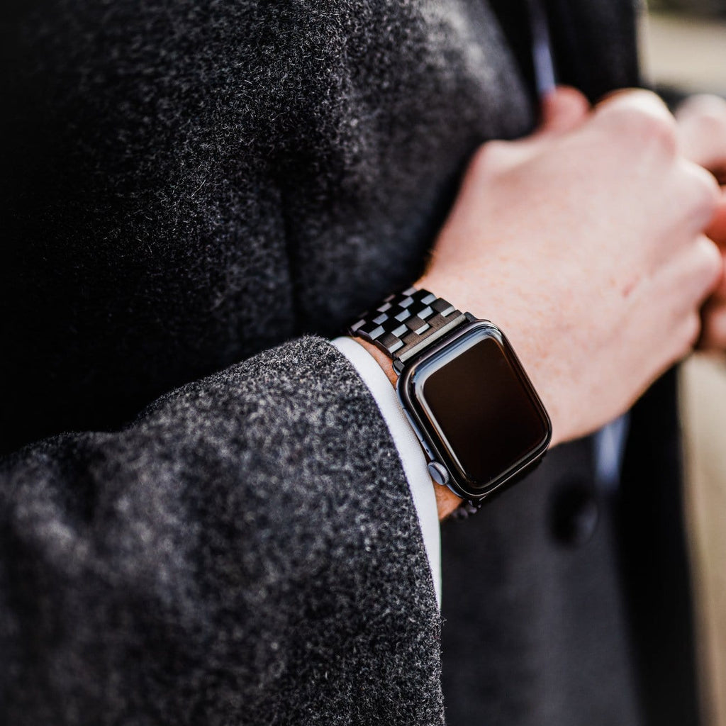 Black metal link strap on an Apple Watch worn on a wrist with a gray coat sleeve