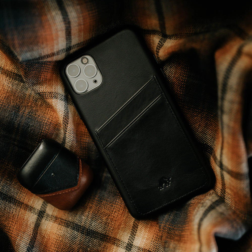 Black leather iPhone case with card slots on a plaid background