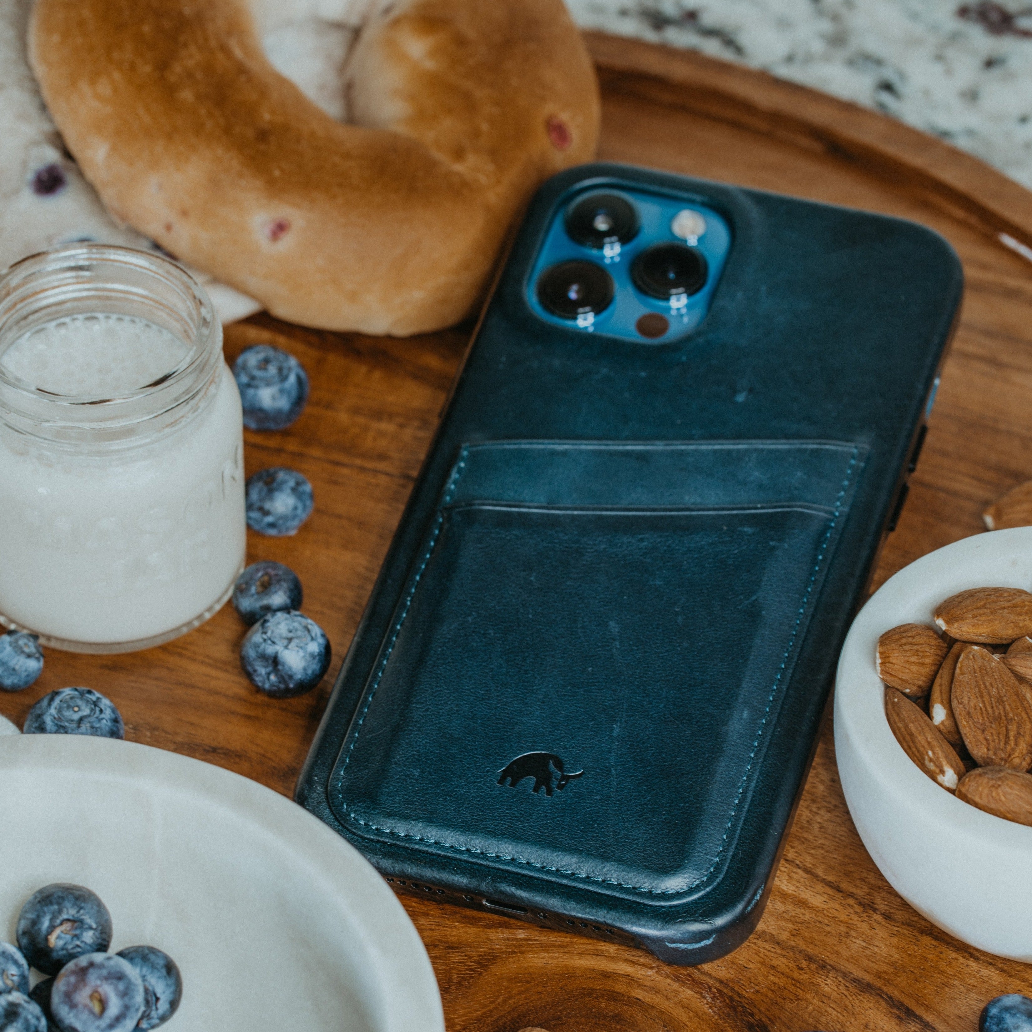Ocean leather minimalist phone wallet with card pocket on wooden board beside blueberries, MASON JAR, and almonds