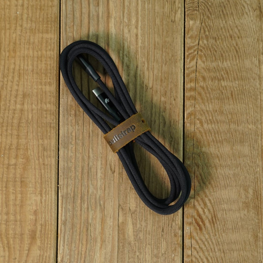 Black charging cable with leather strap labeled 'Bullstrap'